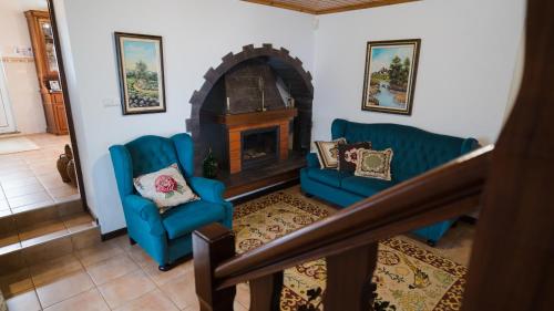a living room with two blue chairs and a fireplace at Quinta Rico in Quatro Ribeiras