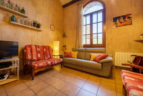 a living room with a couch and a tv at Casa rural ideal para familias y amigos in Serinyà