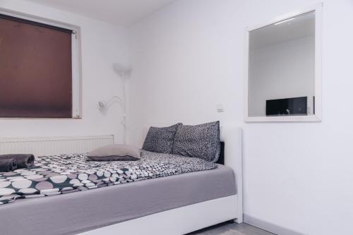a white bedroom with a bed with a window at Apartments Luka in Kragujevac