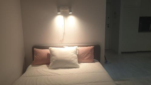 1 cama con 2 almohadas y una luz en la pared en aeropuerto loft polígono, en Manises