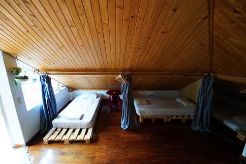 a room with two beds and a wooden ceiling at Jaca Hostel Porto da Cruz in Porto da Cruz
