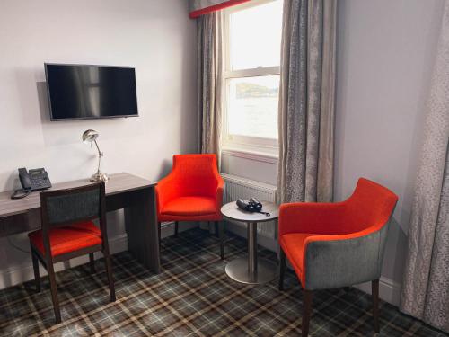 a room with red chairs and a desk and a window at Belmont Llandudno in Llandudno