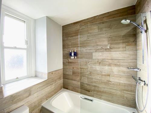 a bathroom with a tub and a toilet and a window at Belmont Llandudno in Llandudno