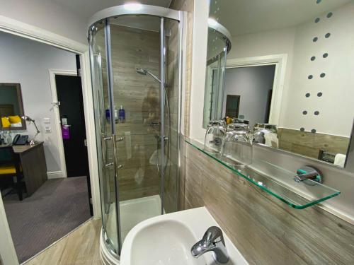a bathroom with a shower and a sink and a mirror at Belmont Llandudno in Llandudno