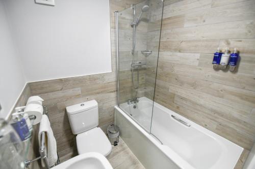 a bathroom with a shower and a toilet and a bath tub at Belmont Llandudno in Llandudno