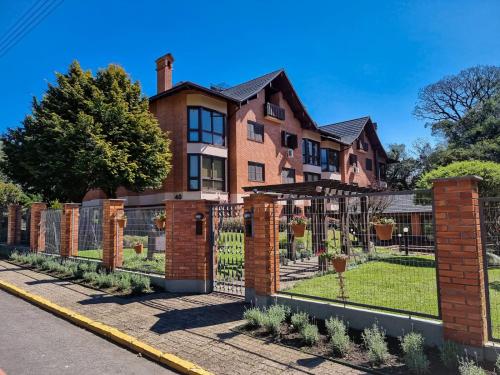 ein Backsteinhaus mit einem schmiedeeisernen Zaun in der Unterkunft Duplex aconchegante no Buganvilias Flat in Gramado