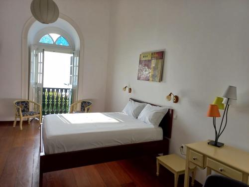 Schlafzimmer mit einem Bett, einem Tisch und einem Fenster in der Unterkunft Hotel Savana in São Filipe