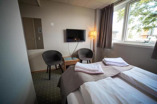 um quarto de hotel com uma cama e duas cadeiras e uma televisão em Torp Hotel em Sandefjord