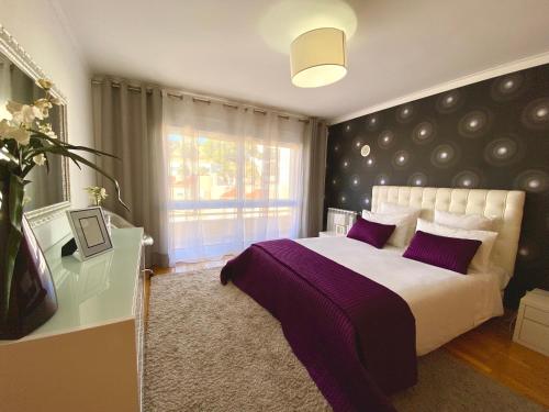 a bedroom with a large bed with purple pillows at Jardins da Parede 211 in Parede