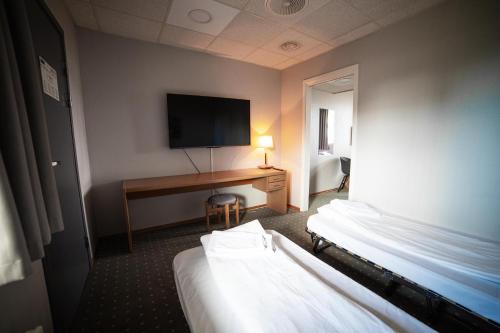 a hotel room with two beds and a desk with a television at Torp Hotel in Sandefjord