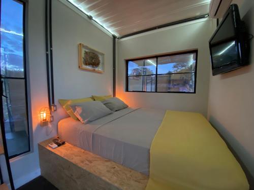 a bedroom with a bed and a tv and windows at Hospedaria BOCA DO MATO - CONTAINER in Mambaí
