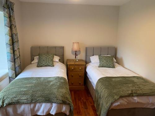 a bedroom with two beds and a lamp on a dresser at Delightful stone barn, with superb views, Ramsgill in Pateley Bridge