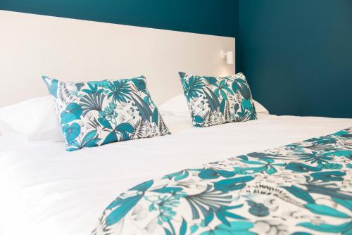 a bed with blue and white sheets and pillows at Le Clos des Bleynoux in Saint-Étienne-de-Fontbellon