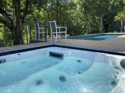 a jacuzzi tub with two chairs and a deck at Le Clos des Bleynoux in Saint-Étienne-de-Fontbellon