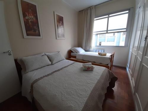 um quarto com uma cama, uma cadeira e uma janela em Apartamento Copacabana Posto 5 no Rio de Janeiro