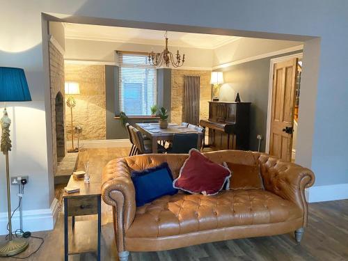 Una sala de estar con un sofá de cuero marrón y una mesa. en Farndale House-Hot tub, en Amble