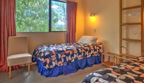 a bedroom with a bed and a window and a chair at 34 Denby Place in Hanmer Springs