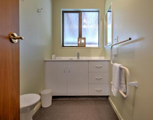 a bathroom with a sink and a toilet and a window at 34 Denby Place in Hanmer Springs