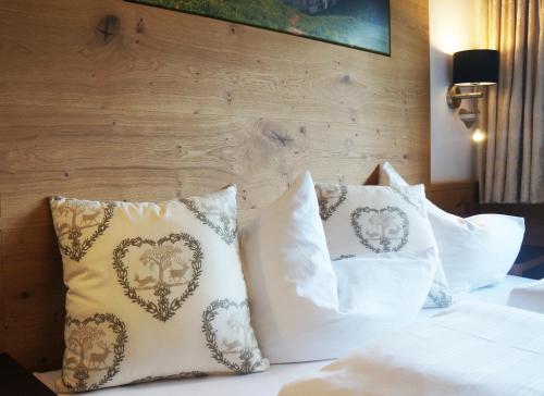 a bed with white pillows and a wooden wall at Aparthotel Landhaus St. Joseph (Indoor Pool) in Mayrhofen