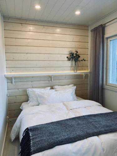 a bedroom with a large white bed with a wooden wall at Ihana asunto - The Nest with Sauna in VAASA in Vaasa