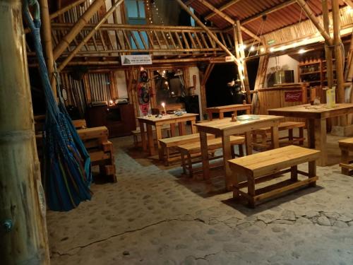 un restaurante con mesas de madera y bancos en una habitación en El Refugio del Oso de Anteojos, en Fómeque