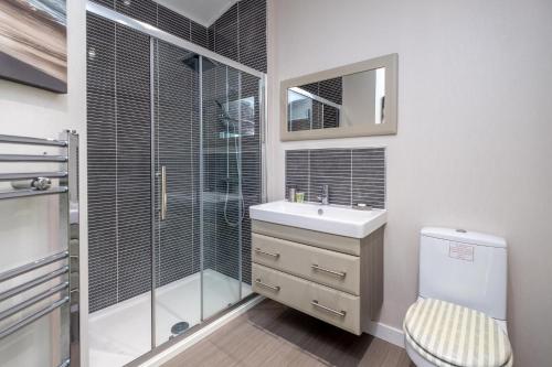 Un baño con inodoro, lavabo y ducha. en Chelsea Lodge - Aldeburgh Coastal Cottages, en Sizewell