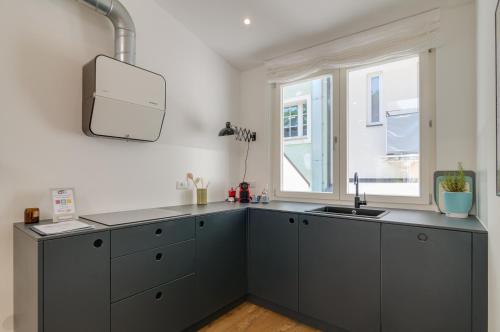 uma cozinha com armários cinzentos e uma janela em Sonnenuhr Bolzano Apartments em Bolzano