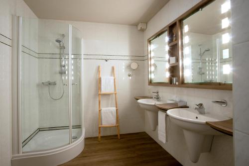 ein Badezimmer mit zwei Waschbecken und einer Glasdusche in der Unterkunft Hotel Mardaga in As