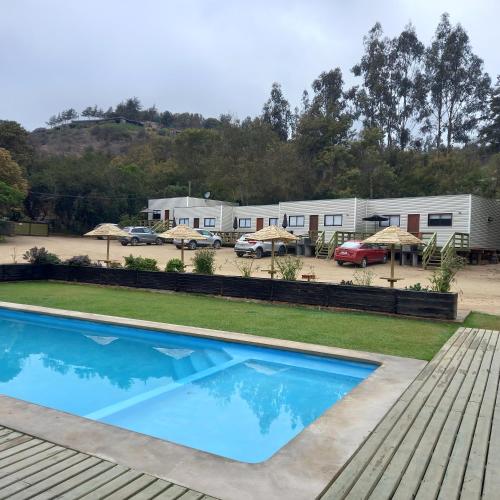 a swimming pool in front of a trailer park at cabañas laguna de zapallar maitencillo in Zapallar
