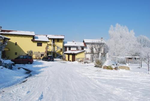a snow covered street in a village with houses at Agriturismo Tra Serra E Lago in Roppolo