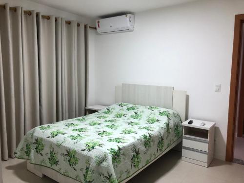 een slaapkamer met een bed met een groene en witte deken bij Residencial Ykutiba Imbassaí in Imbassai