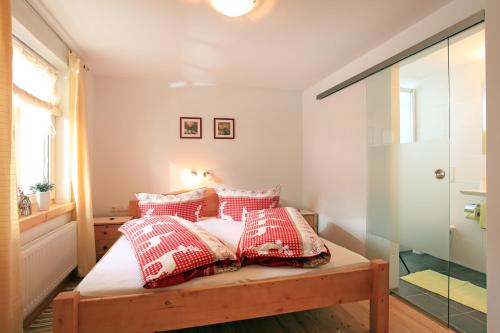 a bedroom with a bed with red and white pillows at Migglwieshof in Kelchsau