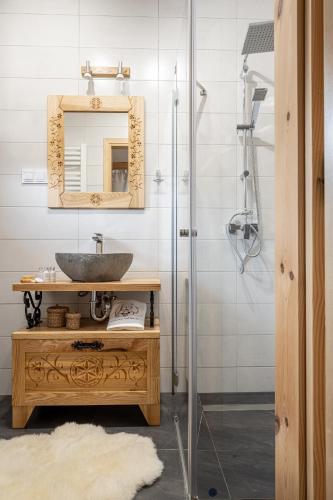 a bathroom with a sink and a mirror and a shower at Domek Chatka Góralki in Poronin