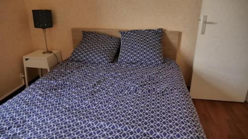 a bed with a purple comforter and two pillows at Appartement T3 in Rennes