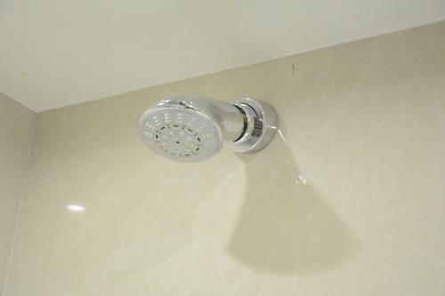 a shower head on a wall with a shadow at Hotel Grand Godwin - Free Airport Pick-Up in New Delhi