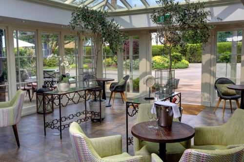 un salón acristalado con mesas, sillas y ventanas en Banbury Wroxton House Hotel en Banbury