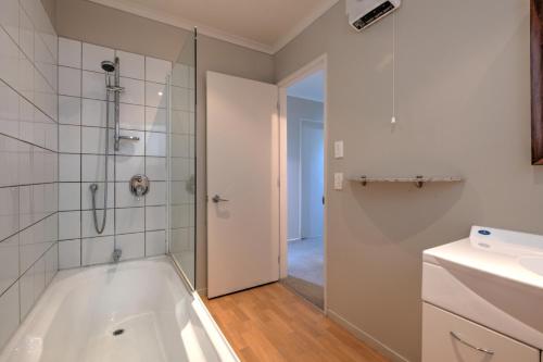een badkamer met een bad, een douche en een wastafel bij 9a Tarndale Place in Hanmer Springs