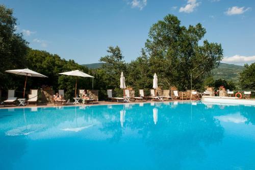 a large blue swimming pool with chairs and umbrellas at Agriturismo Azienda Agricola Il Pozzo in Capolona