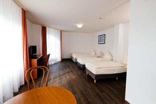 a room with three beds and a table and chairs at Apart Hotel Sehnde in Sehnde