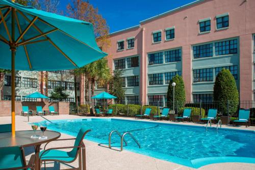 ein Pool in einem Hotel mit Stühlen und einem Sonnenschirm in der Unterkunft Sonesta ES Suites New Orleans Convention Center in New Orleans