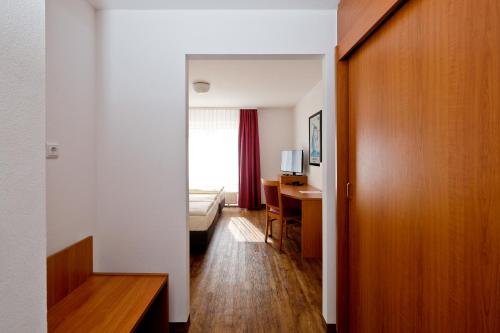 a hotel room with a bed and a desk and a door at Apart Hotel Sehnde in Sehnde