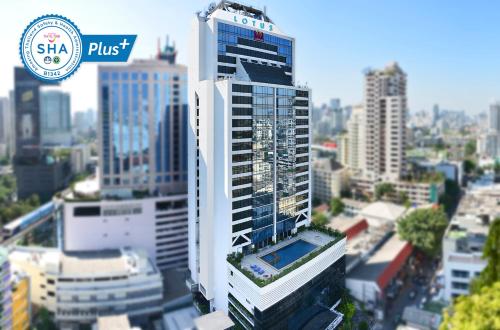 a tall white building in a city with buildings at Bangkok Hotel Lotus Sukhumvit 33 by Compass Hospitality in Bangkok