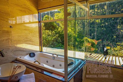 ein Bad mit einer Badewanne und einem großen Fenster in der Unterkunft Chácara Vovô Elson Fonseca - um refúgio nas Montanhas Capixabas in Marechal Floriano