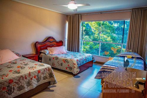 ein Schlafzimmer mit zwei Betten und einem großen Fenster in der Unterkunft Chácara Vovô Elson Fonseca - um refúgio nas Montanhas Capixabas in Marechal Floriano