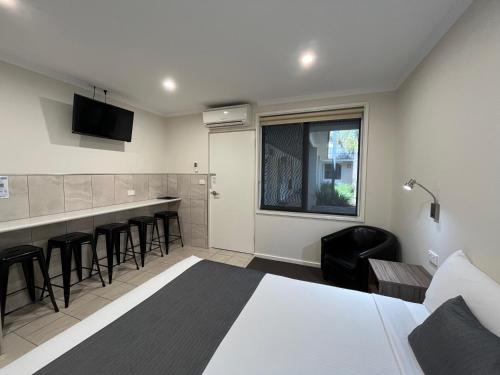 a hotel room with a bed and a bar with stools at Ryley Motor Inn in Wangaratta