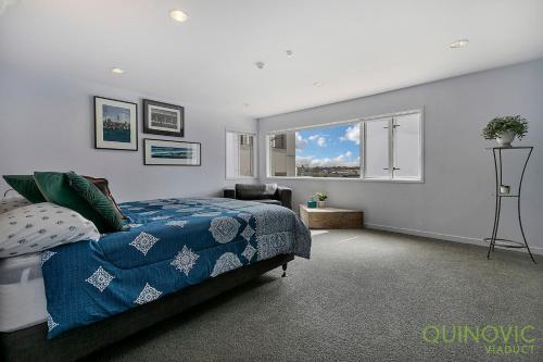 a bedroom with a bed with a blue comforter and a window at QV Stays Stunning Downtown Executive Penthouse in Auckland