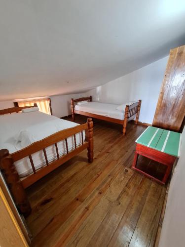 two beds and a table in a room with wooden floors at Hotel Caribbean View in Bastimentos