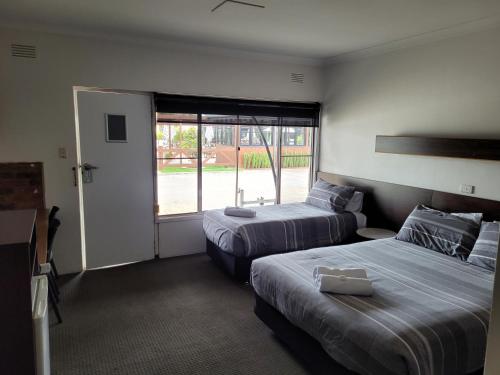 a hotel room with two beds and a window at Palm and Pawn Motor Inn in North Wagga