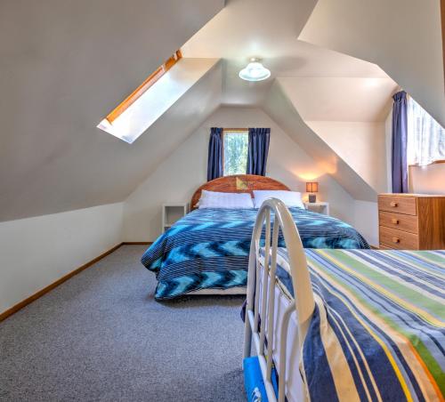 Schlafzimmer im Dachgeschoss mit einem Bett und einem Fenster in der Unterkunft 18b Alpine Avenue in Hanmer Springs