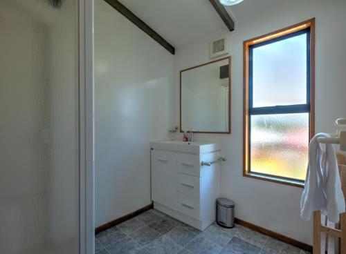 ein Badezimmer mit Waschbecken, Spiegel und Fenster in der Unterkunft 18b Alpine Avenue in Hanmer Springs